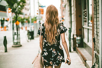 Woman in Floral Dress Walking Down City Street