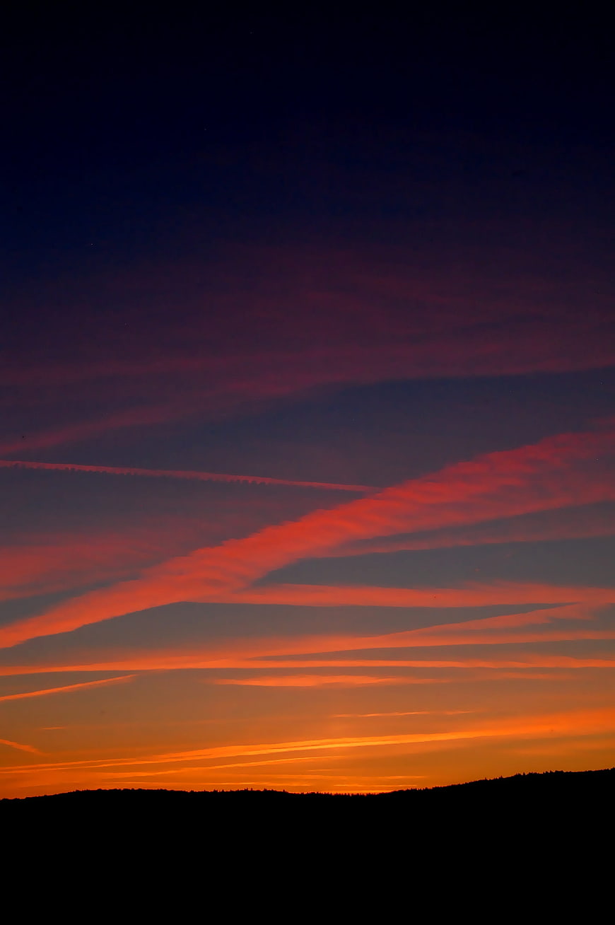 Vibrant orange and purple sunset sky over dark silhouette