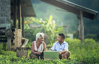Senior woman and boy using laptop in rural village