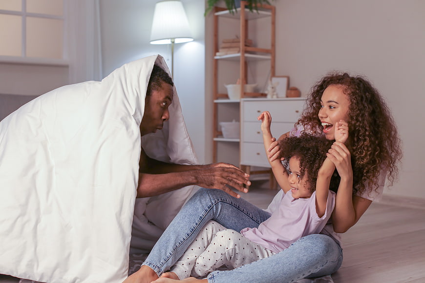 Happy family playing monster game with blanket at home