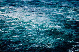 Aerial view of turbulent blue ocean waves with surfers
