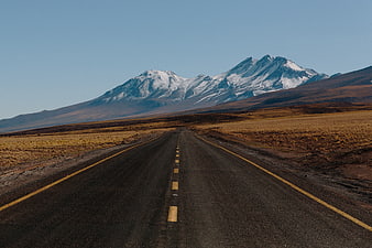 Empty Road Leading to Snow-Capped Mountain Peaks