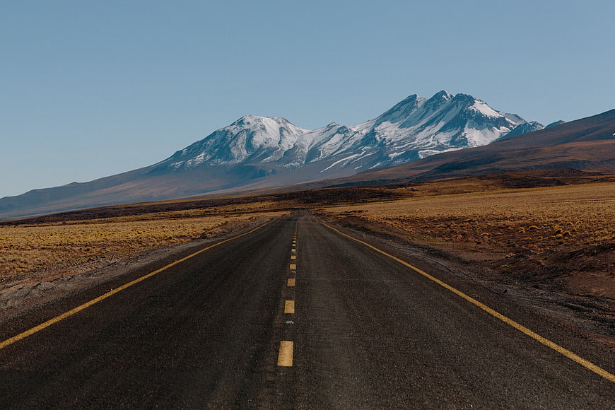 Empty Road Leading to Snow-Capped Mountain Peaks