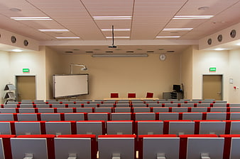 Empty university lecture hall with red chairs and whiteboard