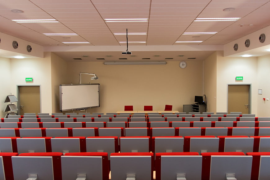 Empty university lecture hall with red chairs and whiteboard
