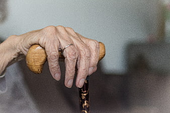 Close-up of elderly woman's hands gripping a wooden walking stick