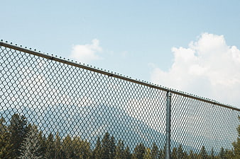 Chain link fence against blue sky with mountains