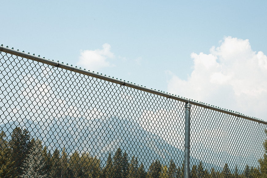 Chain link fence against blue sky with mountains