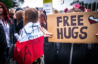 Protestor holding Free Hugs sign with peace gesture