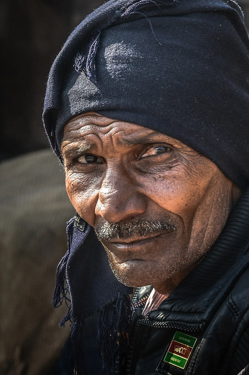 Close-up portrait of elderly man with weathered face and black beanie