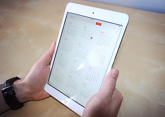 Hands holding white tablet with digital calendar app