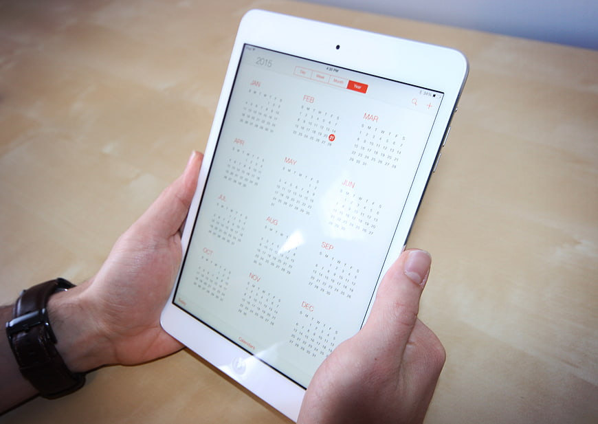 Hands holding white tablet with digital calendar app