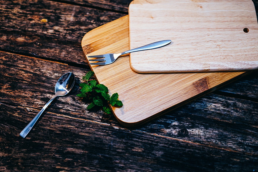 Wooden cutting boards with silverware and mint on rustic table