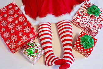 Santa elf legs with striped socks and Christmas gifts