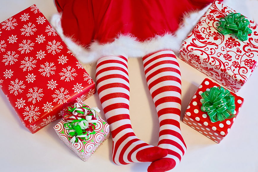 Santa elf legs with striped socks and Christmas gifts