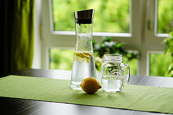 Glass carafe with lemon water and mason jar on green table runner