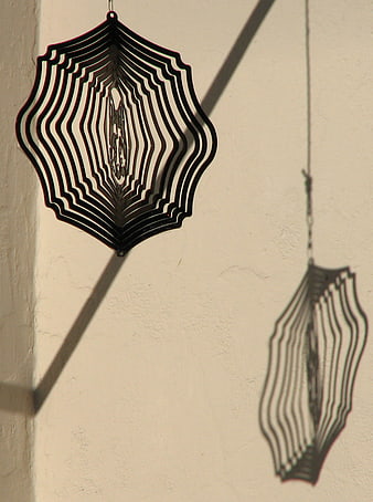 Black metal spider web mobile casting shadow on wall