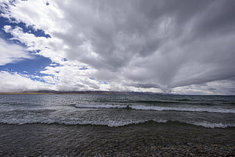 Dramatic Clouds Over a Rocky Lake Shore with Distant Mountains