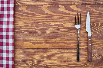 Fork and knife on wooden table with red checkered napkin