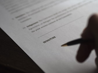 Hand holding pen ready to sign a business contract document