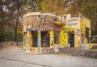Abandoned yellow building covered in graffiti in autumn park