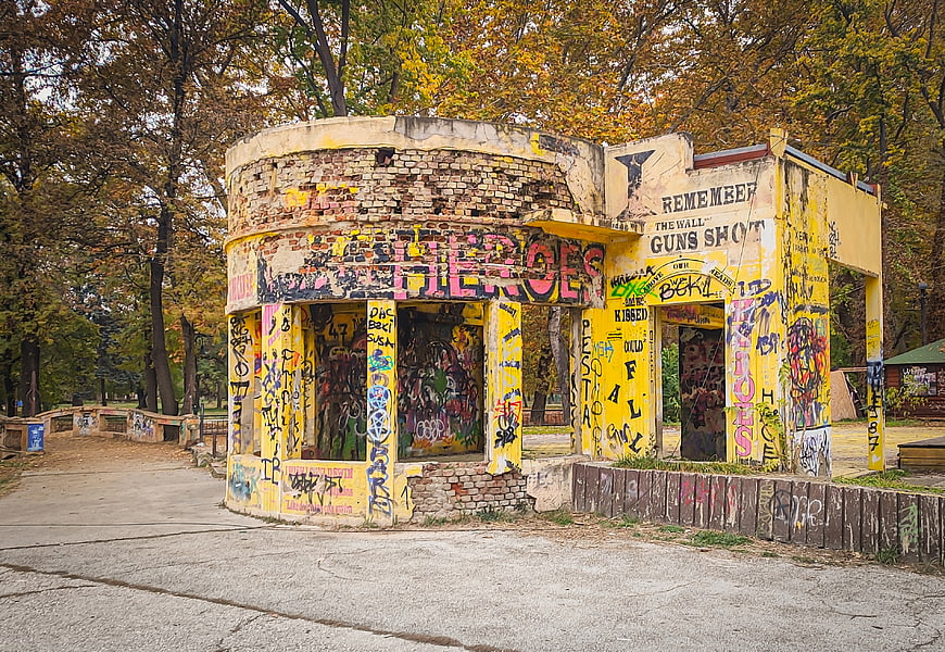 Abandoned yellow building covered in graffiti in autumn park