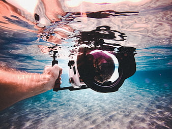 Underwater Photographer Holding Camera in Clear Blue Ocean Water