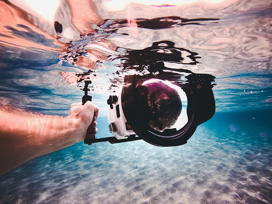 Underwater Photographer Holding Camera in Clear Blue Ocean Water