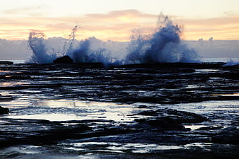 Dramatic Ocean Waves Crashing on Rocky Shore at Sunset