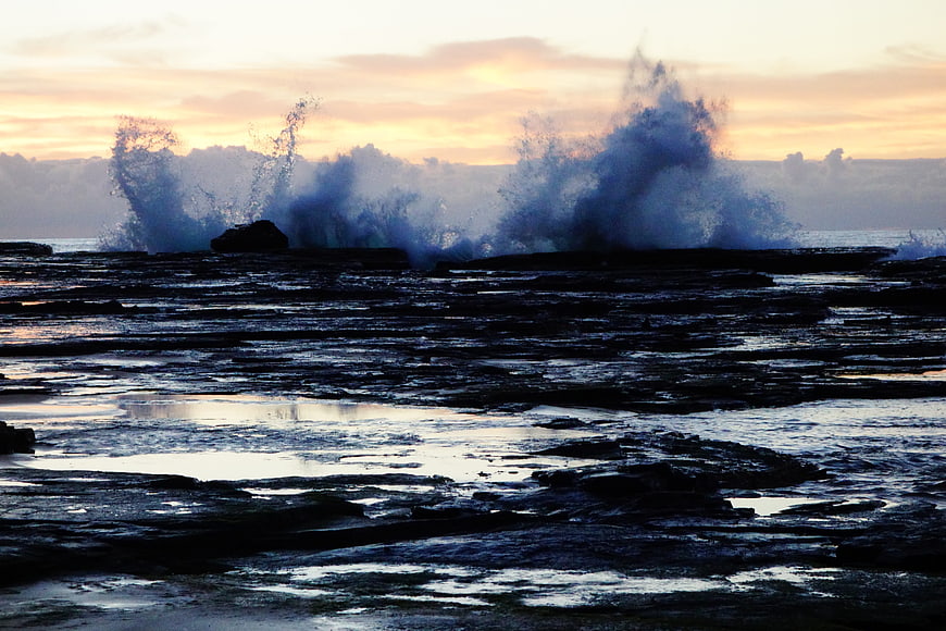 Dramatic Ocean Waves Crashing on Rocky Shore at Sunset