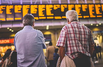 Two Men Checking Train Departure Board at Station