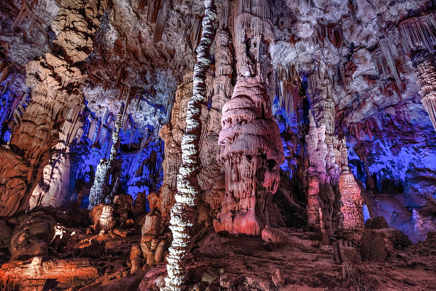 Colorful stalactites and stalagmites in a large cave interior