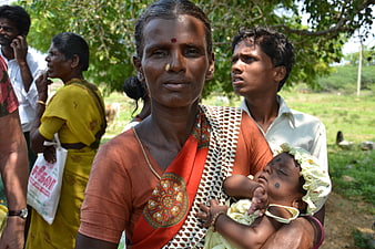 Portrait of Indian woman holding sleeping infant in rural village setting