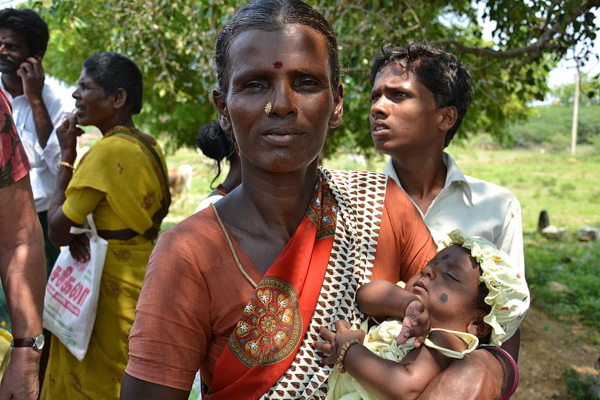 Portrait of Indian woman holding sleeping infant in rural village setting