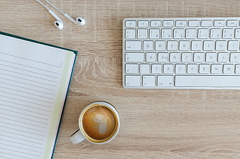 Flat lay of workspace with coffee, keyboard, and notebook