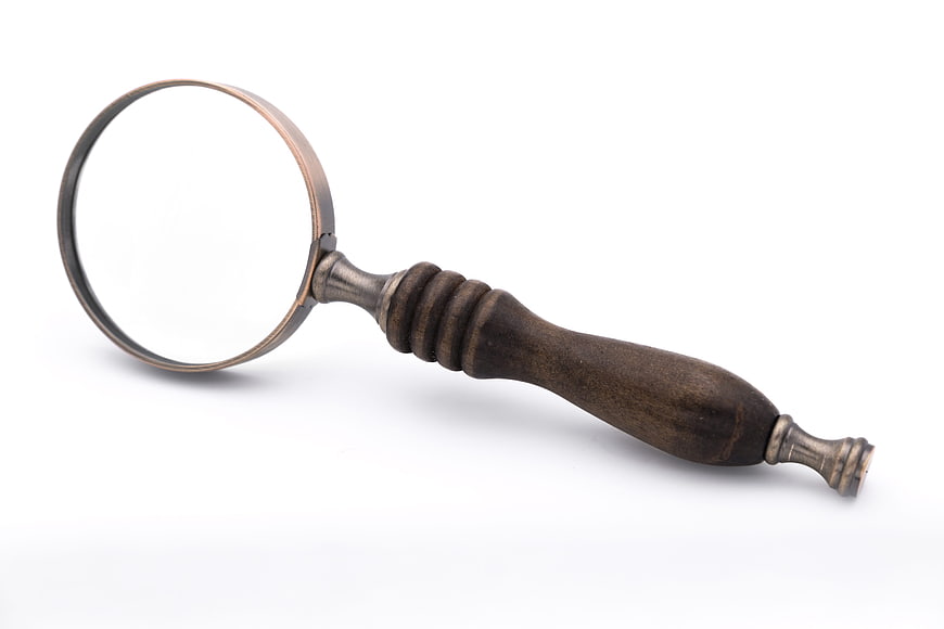 Antique wooden magnifying glass with brass rim on white background