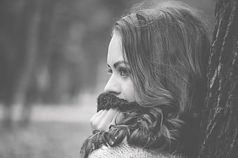 Pensive woman leaning against tree in black and white