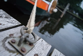 Close-up of rope tied to metal cleat on wooden dock