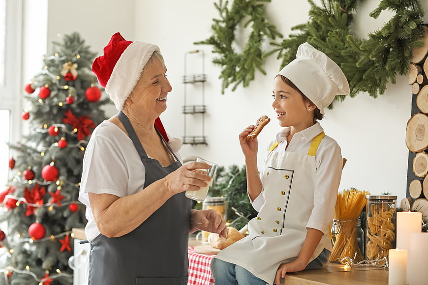 Grandmother and granddaughter baking Christmas cookies in festive kitchen