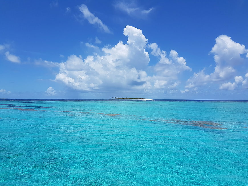 Tropical turquoise lagoon with distant island and blue sky