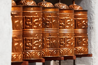 Row of ornate copper Tibetan Buddhist prayer wheels