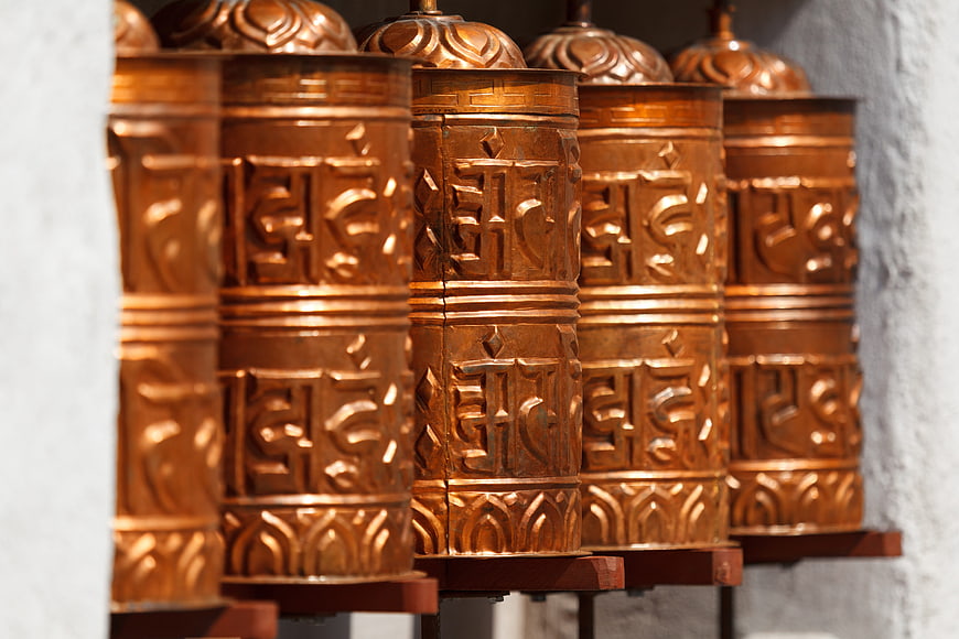 Row of ornate copper Tibetan Buddhist prayer wheels