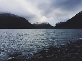 Dramatic Snow-Capped Mountains Overlapping a Misty Fjord