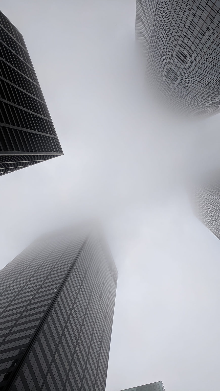 Low angle view of skyscrapers disappearing into thick fog
