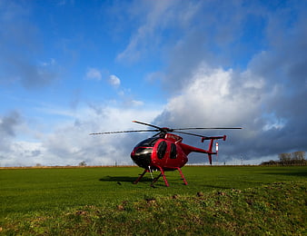 Red Helicopter on Green Field Under Dramatic Sky