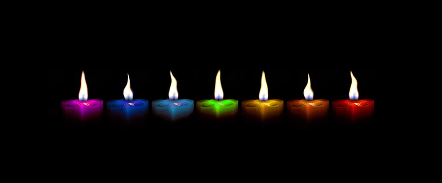 Row of Multicolored Tea Light Candles on Black Background