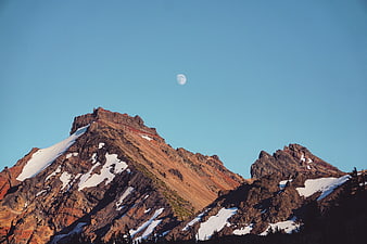 Snowy Mountain Peaks with Moon in Blue Sky