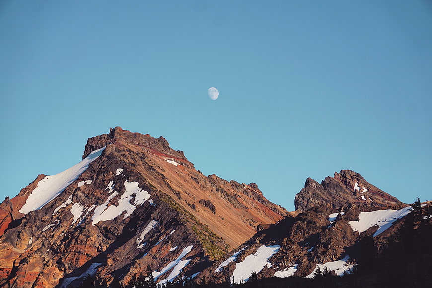 Snowy Mountain Peaks with Moon in Blue Sky