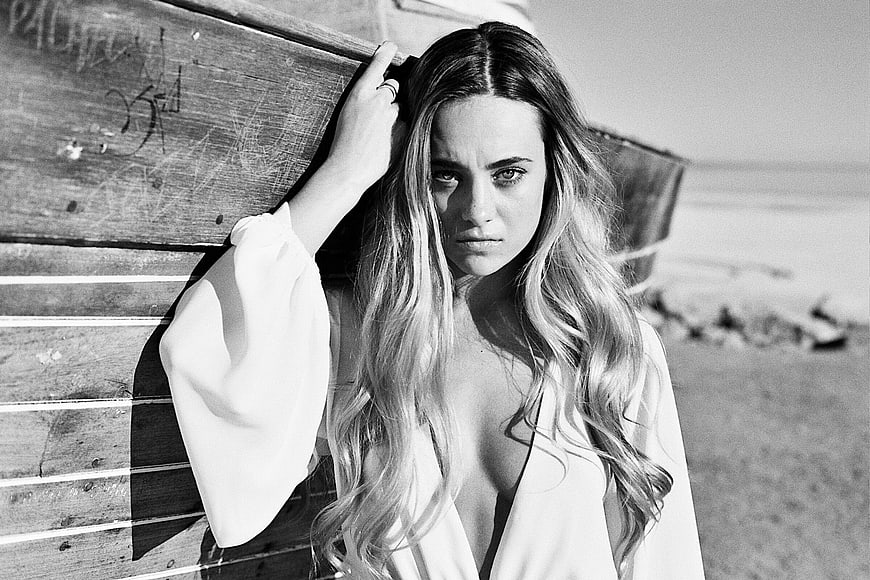 Black and white portrait of woman leaning on boat at beach