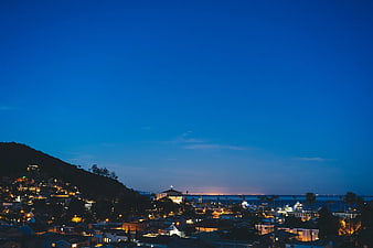 Nighttime coastal cityscape with hillside homes and ocean view